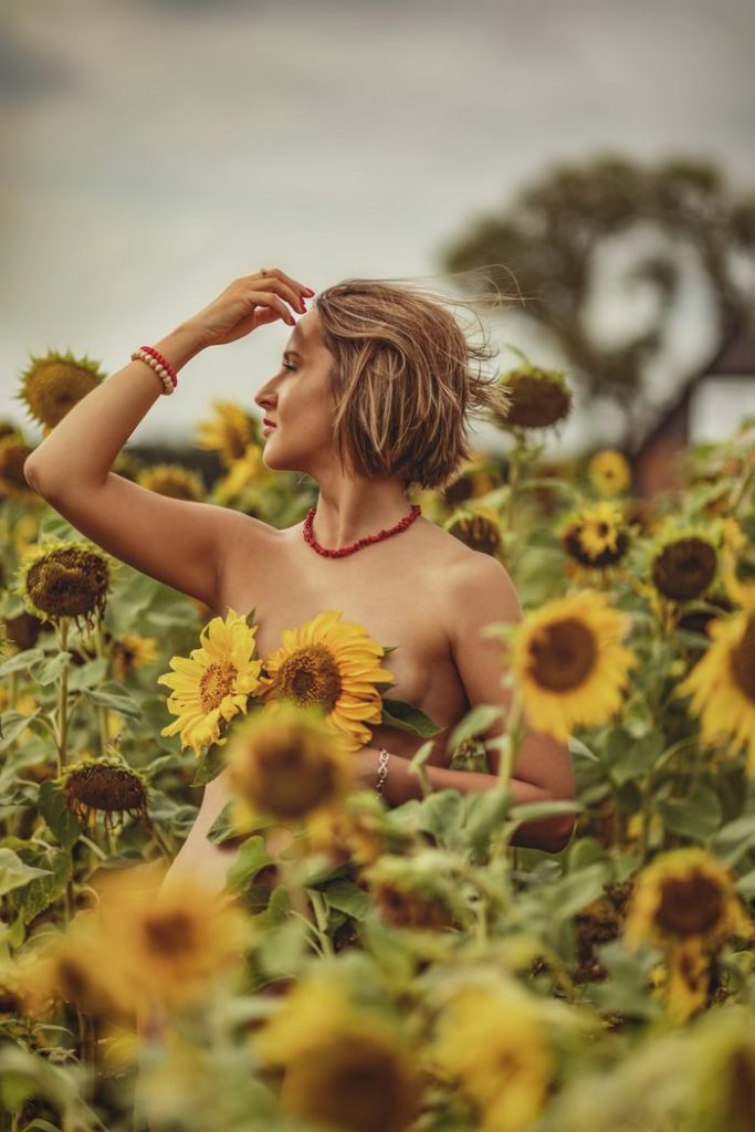A woman stands gracefully amidst a vibrant sunflower field, embracing nature's beauty.